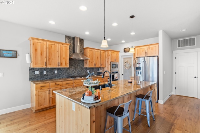 kitchen with wall chimney exhaust hood, stainless steel appliances, sink, and light wood-type flooring