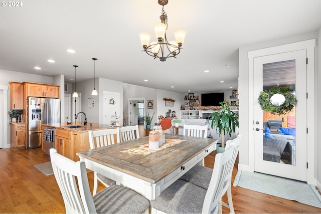 dining space with a notable chandelier, sink, and light wood-type flooring