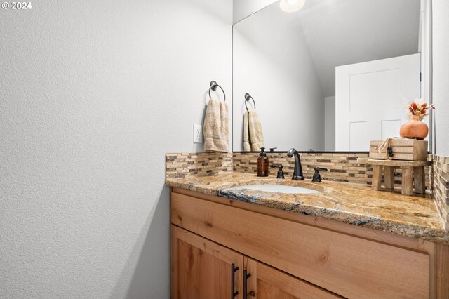 bathroom featuring vanity, lofted ceiling, and tasteful backsplash