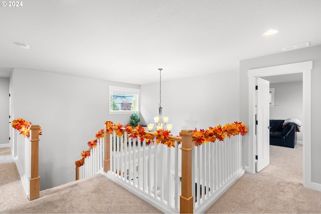 hallway with a notable chandelier and light carpet