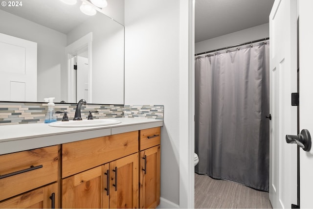 bathroom featuring vanity, toilet, and tasteful backsplash