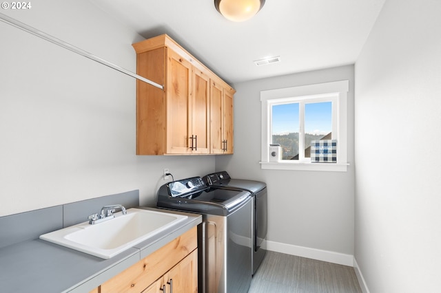 washroom featuring sink, washer and clothes dryer, and cabinets