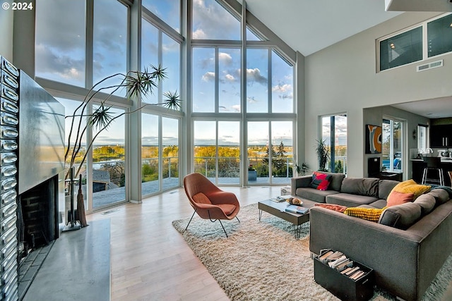 living room featuring a high ceiling, wood finished floors, visible vents, and floor to ceiling windows