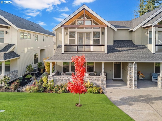 view of front of house with roof with shingles, central air condition unit, a porch, a front yard, and a balcony