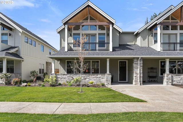 craftsman-style home featuring a porch, a front lawn, a balcony, and stone siding