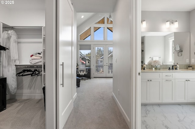 hallway featuring light colored carpet, a sink, baseboards, and recessed lighting