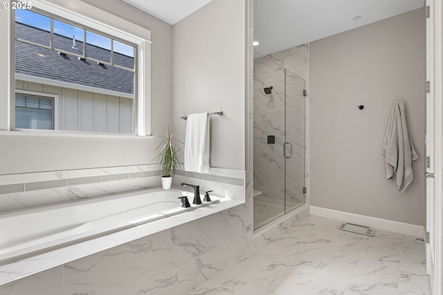 bathroom featuring marble finish floor, a bath, a marble finish shower, and baseboards