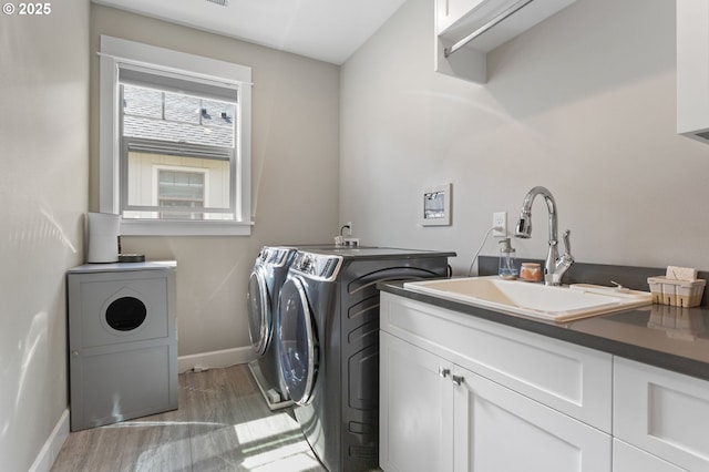 laundry room with cabinet space, baseboards, washing machine and dryer, and a sink