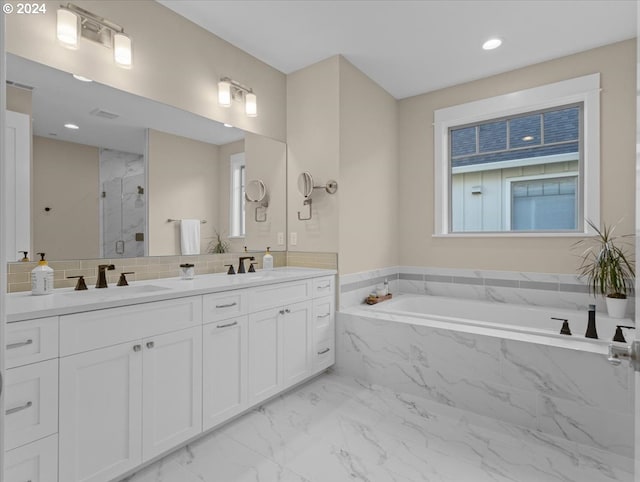 bathroom with marble finish floor, a garden tub, a marble finish shower, double vanity, and a sink