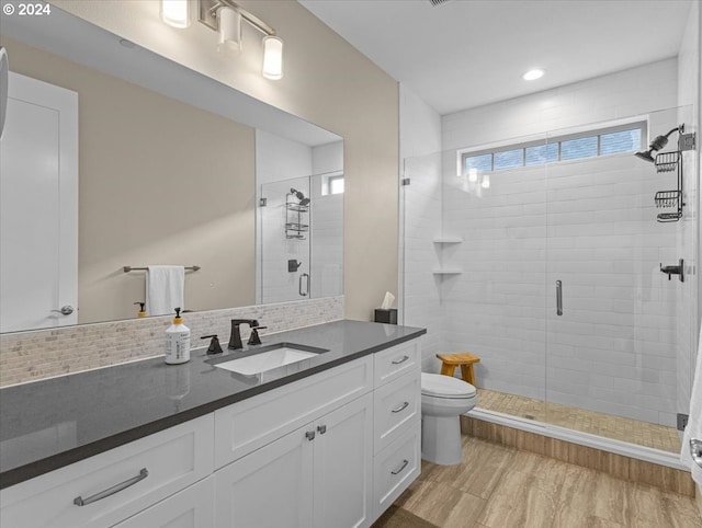 bathroom featuring walk in shower, hardwood / wood-style floors, toilet, decorative backsplash, and vanity