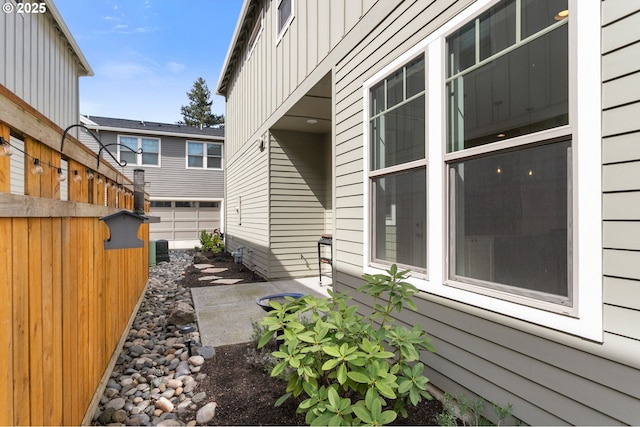 view of side of property with a patio area, fence, cooling unit, and board and batten siding