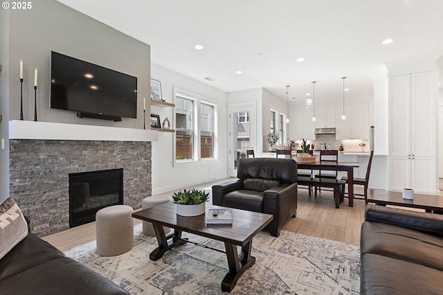 living room with light wood-style flooring, a fireplace, baseboards, and recessed lighting
