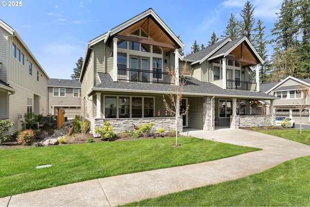 exterior space featuring a front yard, roof with shingles, stone siding, and a balcony