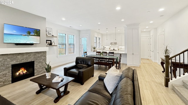 living area featuring light wood-style flooring, recessed lighting, a fireplace, baseboards, and stairs