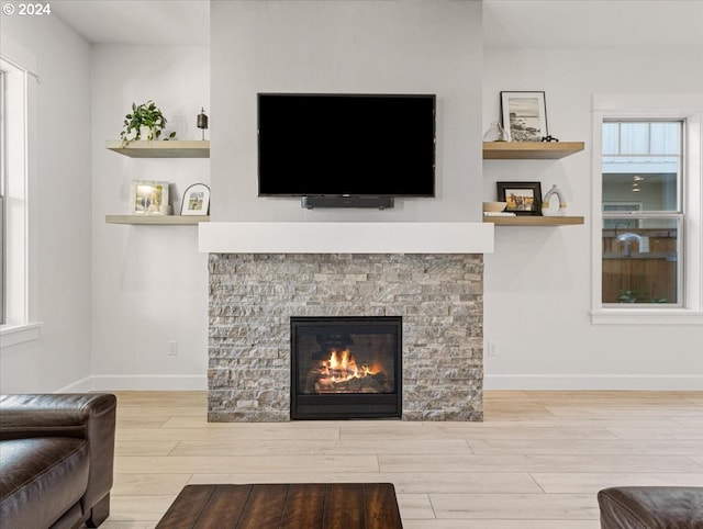 living area featuring built in shelves, a fireplace, baseboards, and wood finished floors