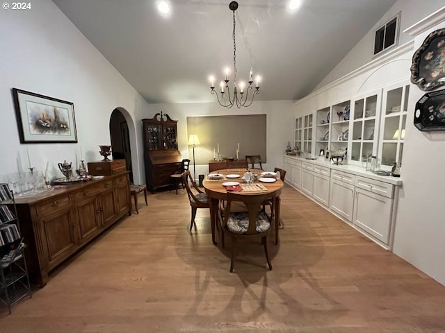 dining space featuring light hardwood / wood-style flooring, vaulted ceiling, and a chandelier