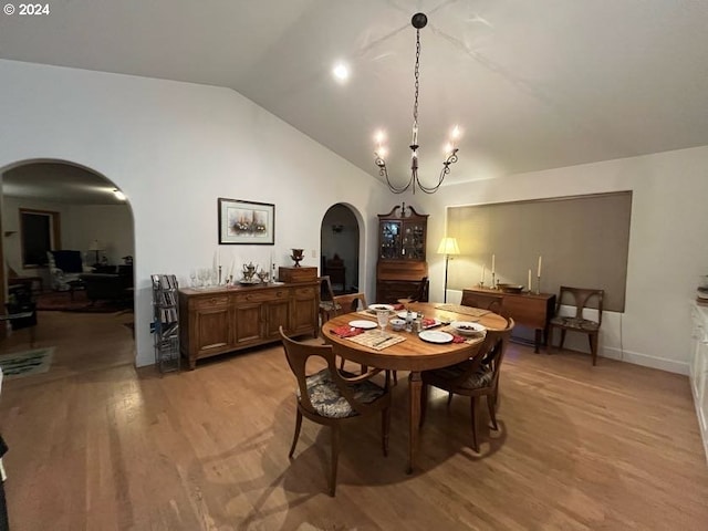 dining room featuring a notable chandelier, vaulted ceiling, and light wood-type flooring