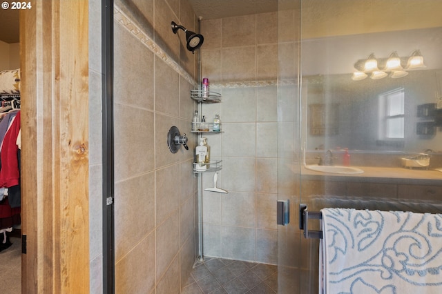 bathroom featuring a shower with shower door and sink