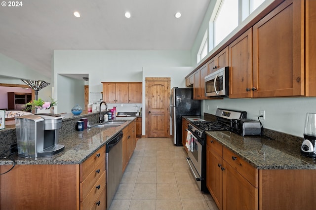 kitchen with dark stone counters, sink, light tile floors, and appliances with stainless steel finishes