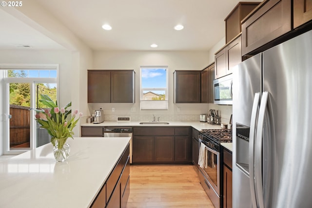 kitchen featuring stainless steel appliances, a sink, plenty of natural light, recessed lighting, and light countertops