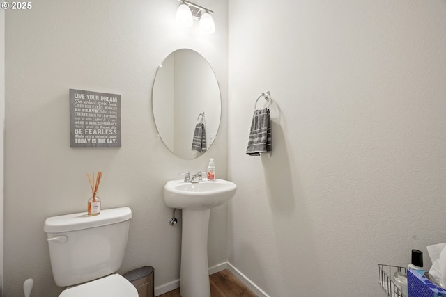 bathroom featuring toilet, wood finished floors, baseboards, and a sink