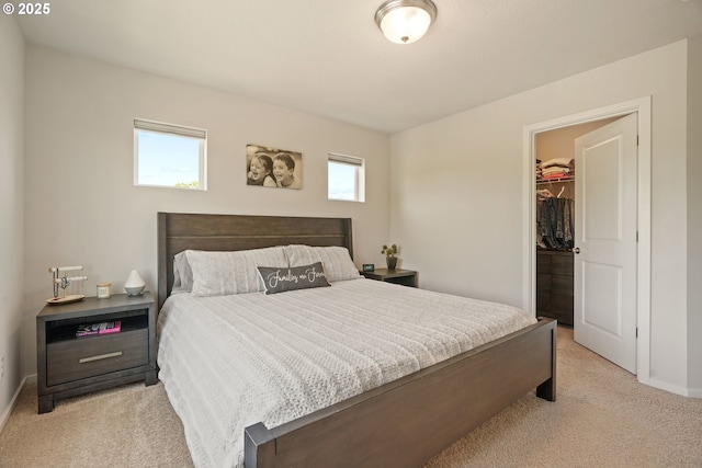 bedroom featuring light carpet, a walk in closet, baseboards, and a closet