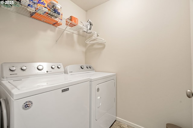 clothes washing area featuring washer and clothes dryer and baseboards