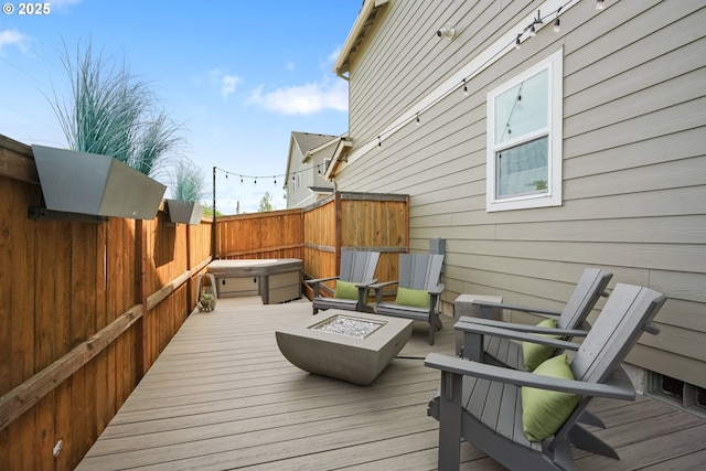 deck featuring a covered hot tub, a fire pit, and fence