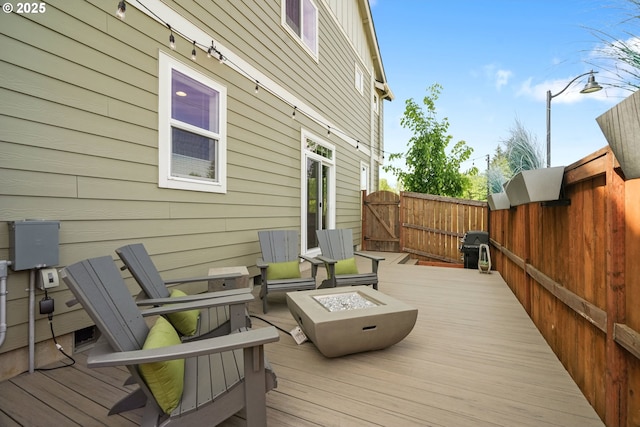 wooden deck featuring an outdoor fire pit, a gate, and fence