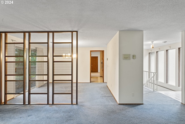 carpeted spare room with a textured ceiling