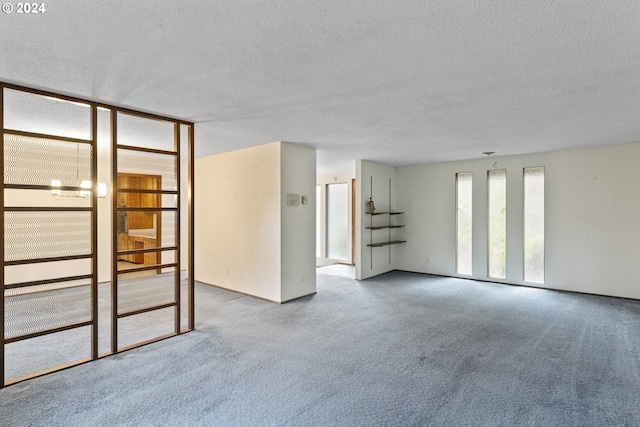 spare room featuring a notable chandelier, a textured ceiling, and carpet