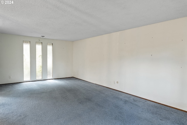 carpeted empty room featuring a textured ceiling