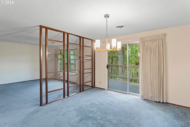 carpeted empty room with an inviting chandelier and a textured ceiling