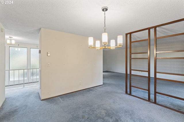 carpeted empty room with a textured ceiling and a chandelier