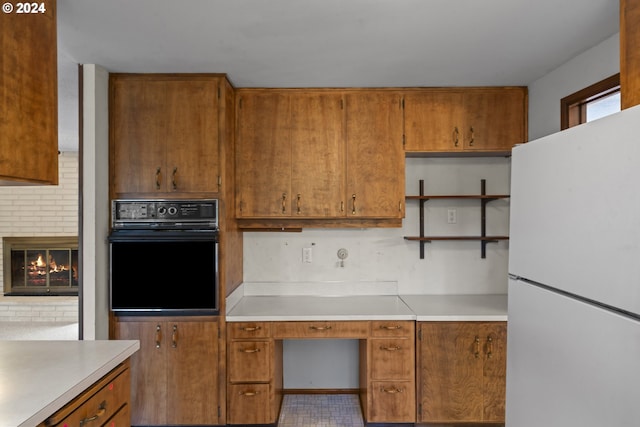 kitchen with decorative backsplash, a brick fireplace, black oven, and white refrigerator