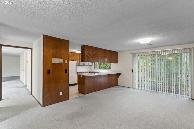 kitchen featuring white fridge, kitchen peninsula, light colored carpet, and plenty of natural light