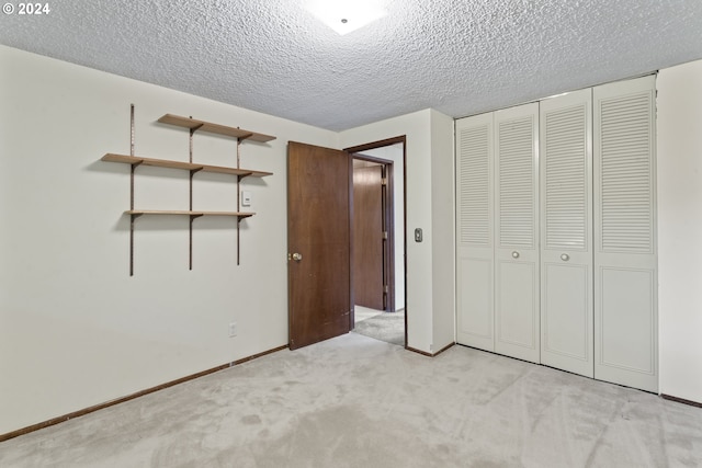 unfurnished bedroom with a closet, a textured ceiling, and light colored carpet