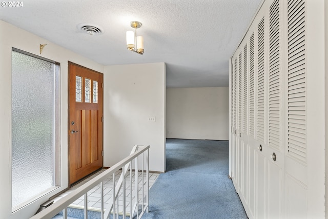 entrance foyer featuring carpet floors, a textured ceiling, and a wealth of natural light