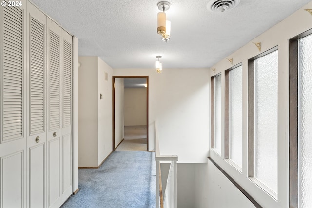 hallway featuring a textured ceiling and light colored carpet