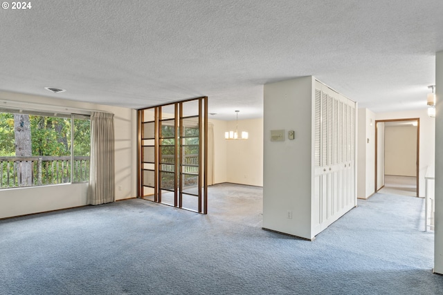 carpeted empty room featuring an inviting chandelier and a textured ceiling