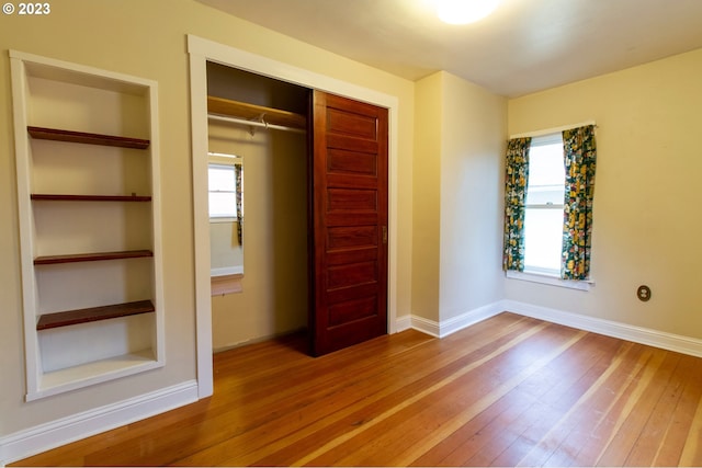 unfurnished bedroom with light hardwood / wood-style floors, multiple windows, and a closet