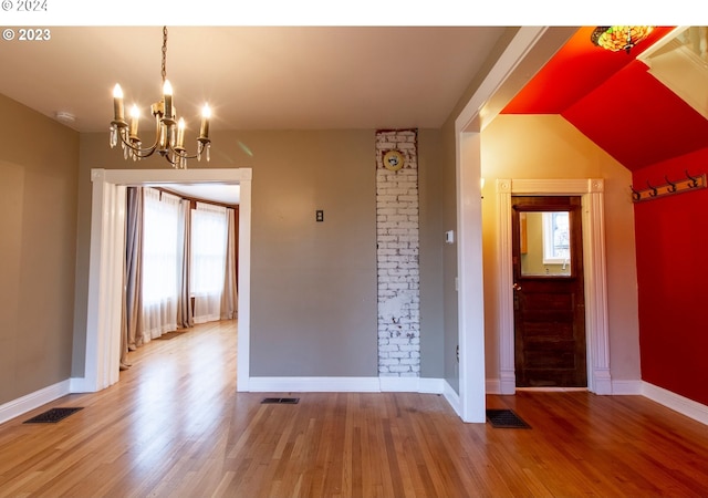 spare room featuring a chandelier, a wealth of natural light, and wood-type flooring