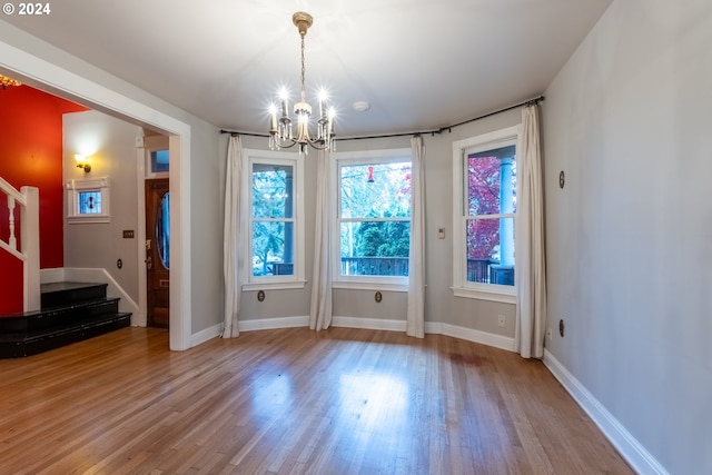 unfurnished dining area with hardwood / wood-style flooring and a chandelier