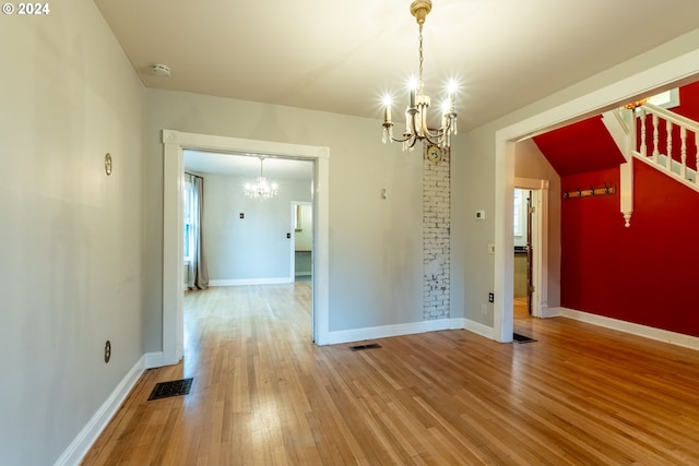 unfurnished dining area featuring wood-type flooring and an inviting chandelier