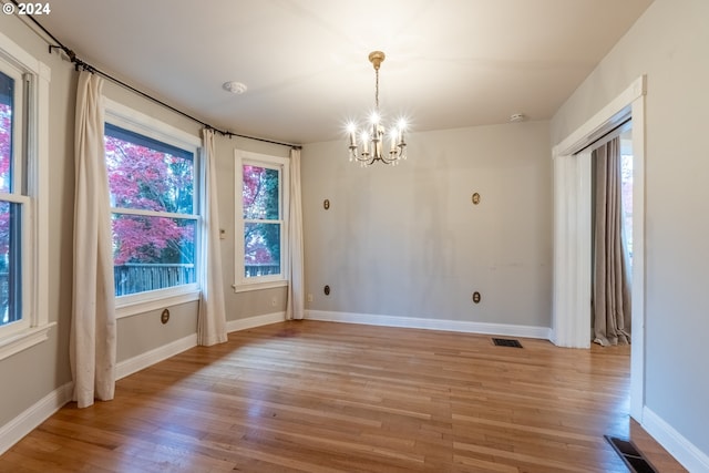 unfurnished dining area with light hardwood / wood-style floors and an inviting chandelier