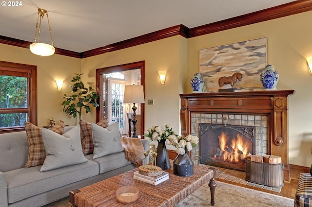 living room with a tiled fireplace, ornamental molding, and light hardwood / wood-style flooring