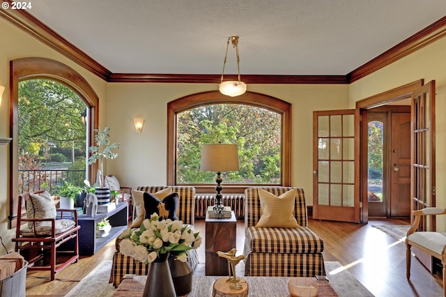 living room with crown molding, french doors, and light wood-type flooring