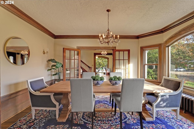 dining area featuring crown molding, a notable chandelier, a textured ceiling, and hardwood / wood-style floors