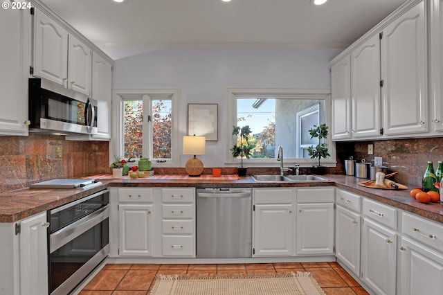 kitchen with appliances with stainless steel finishes, white cabinets, tasteful backsplash, and sink