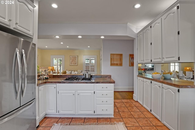 kitchen with kitchen peninsula, white cabinets, stainless steel appliances, and crown molding